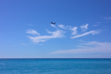 Photo of Airplane flying in beautiful blue sky above wavy sea