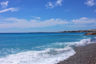 Photo of Beautiful view of wavy sea, city and pebbles on beach