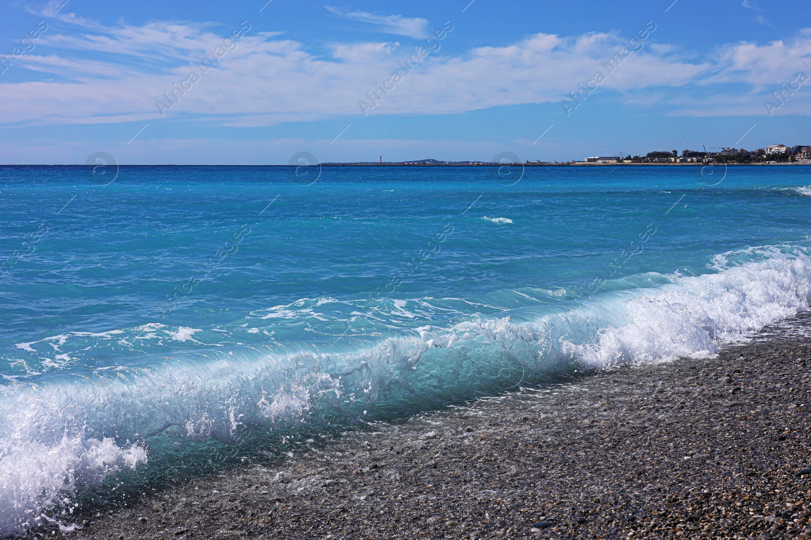 Photo of Beautiful view of wavy sea, city and pebbles on beach