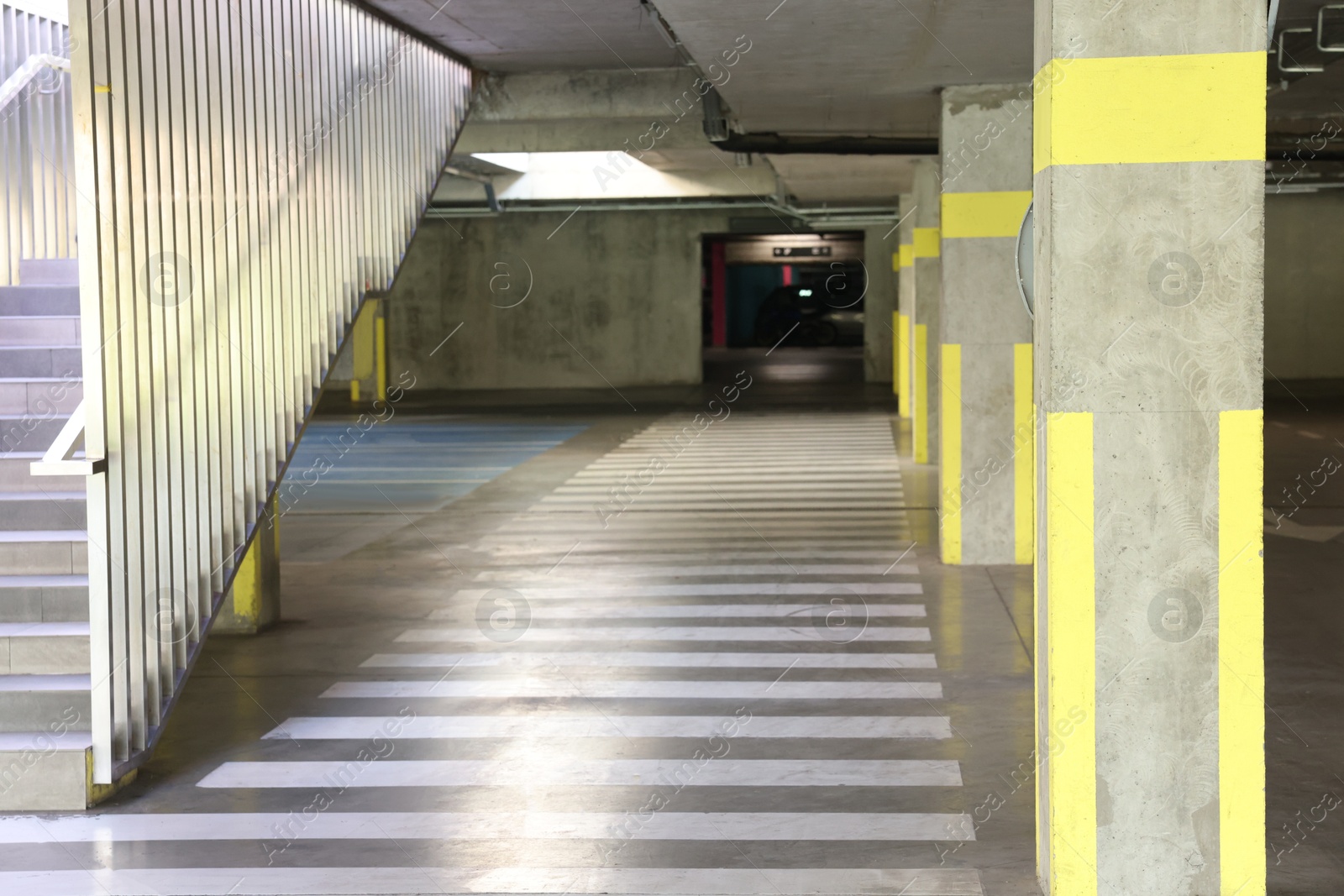 Photo of View of empty underground parking with dedicated spots, pedestrian crossing and stairs