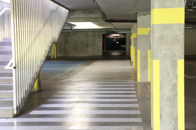 Photo of View of empty underground parking with dedicated spots, pedestrian crossing and stairs