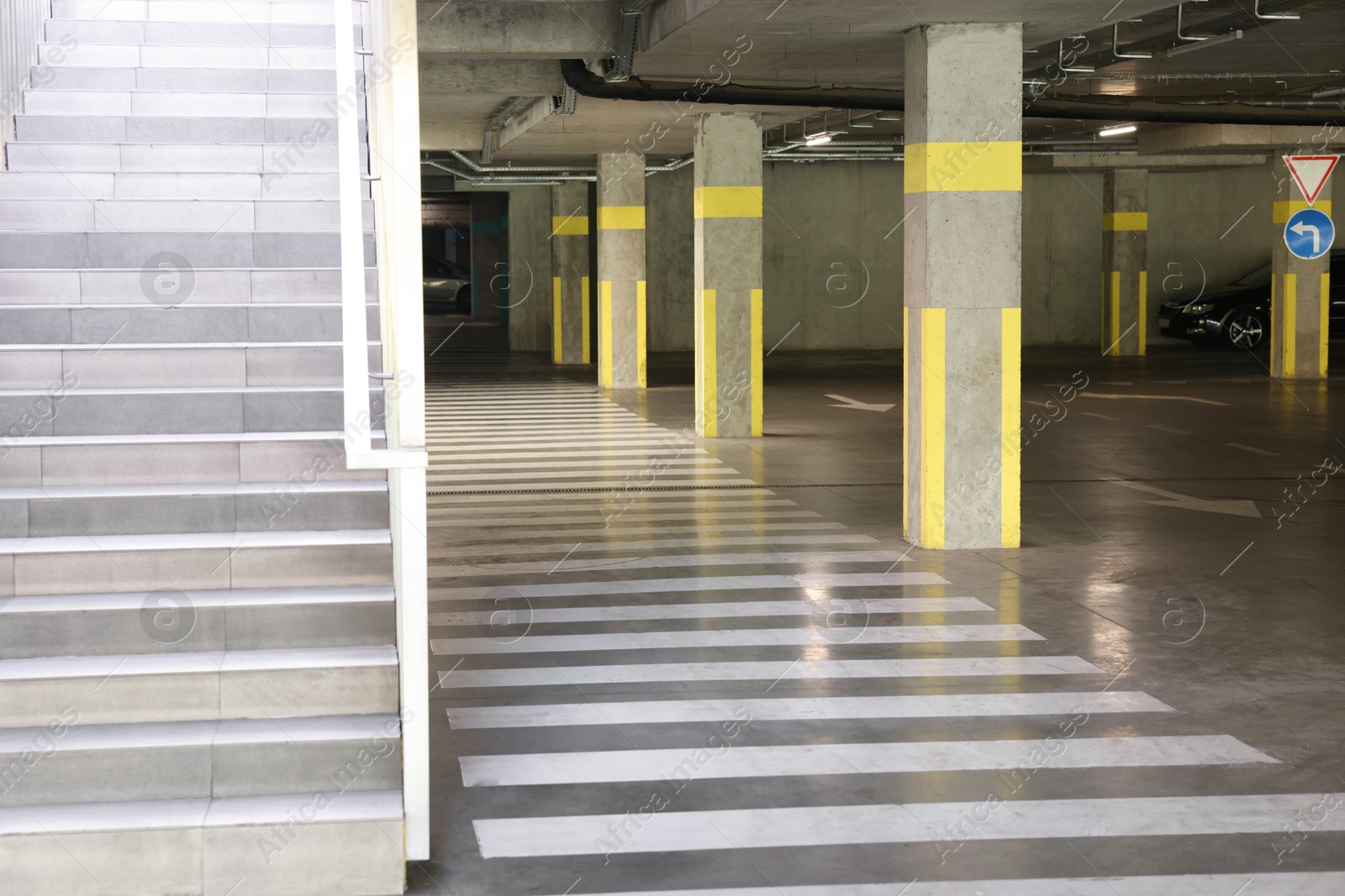 Photo of View of empty underground parking with dedicated spots, pedestrian crossing and stairs