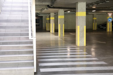 Photo of View of empty underground parking with dedicated spots, pedestrian crossing and stairs