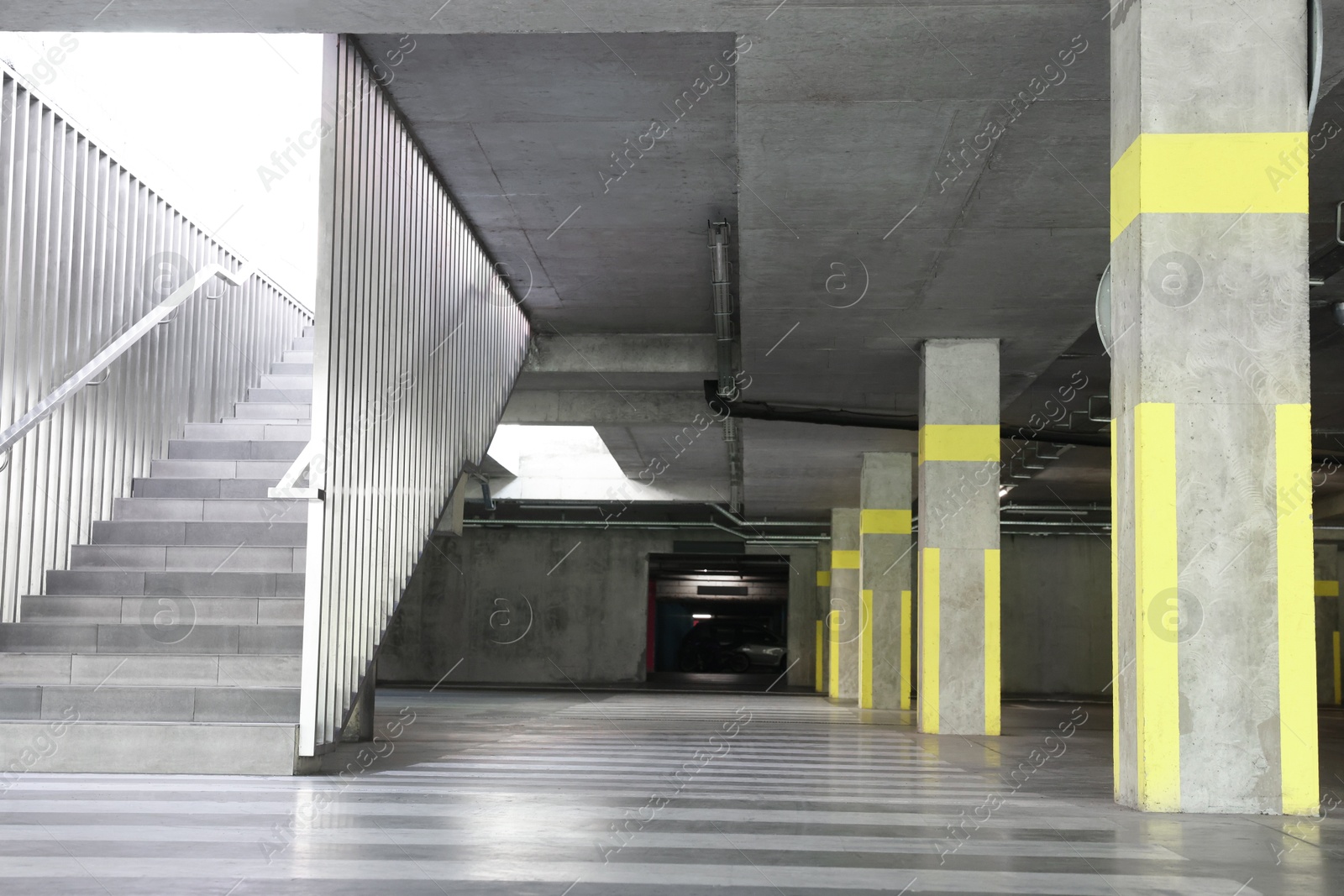 Photo of View of empty underground parking with dedicated spots, pedestrian crossing and stairs