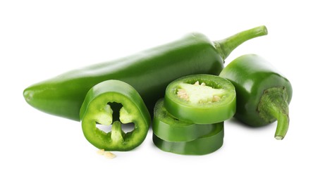 Photo of Whole and sliced green jalapeno peppers isolated on white