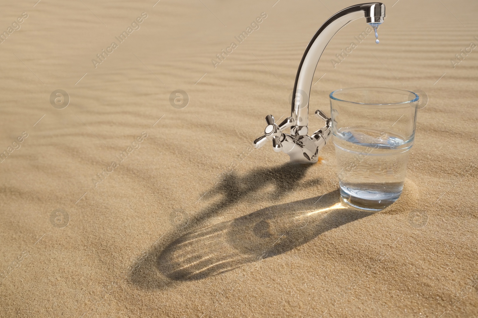 Image of Save water concept. Glass under tap with dripping water in desert