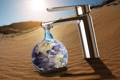Image of Save water concept. Earth under flow of water from tap in desert