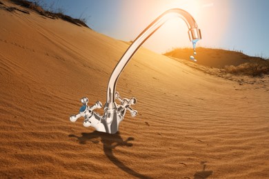 Image of Save water concept. Tap with dripping water in desert under scorching sun