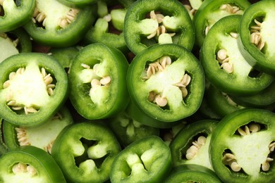 Photo of Fresh green jalapeno pepper slices as background, closeup