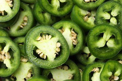 Photo of Fresh green jalapeno pepper slices as background, closeup