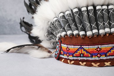 Photo of Traditional warbonnet (Native American chief headdress) on light grey table, closeup