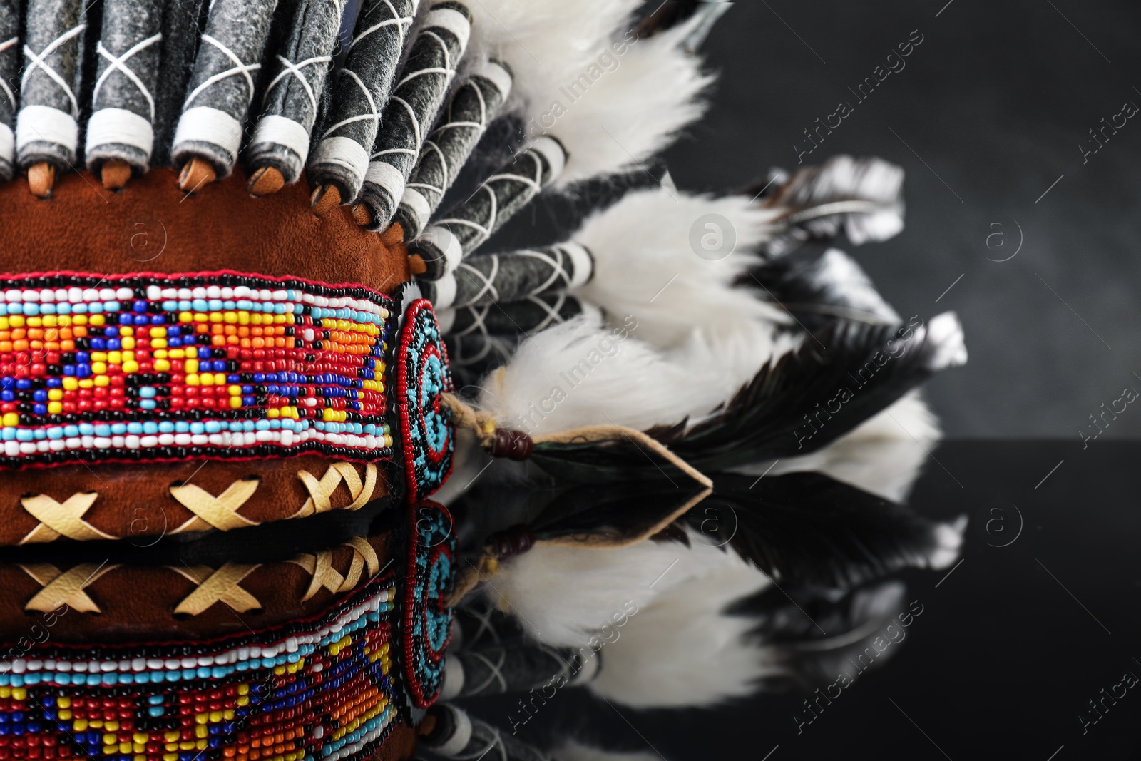Photo of Traditional warbonnet (Native American chief headdress) on black mirror surface, closeup