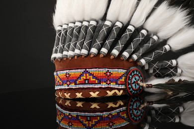Photo of Traditional warbonnet (Native American chief headdress) on black mirror surface, closeup