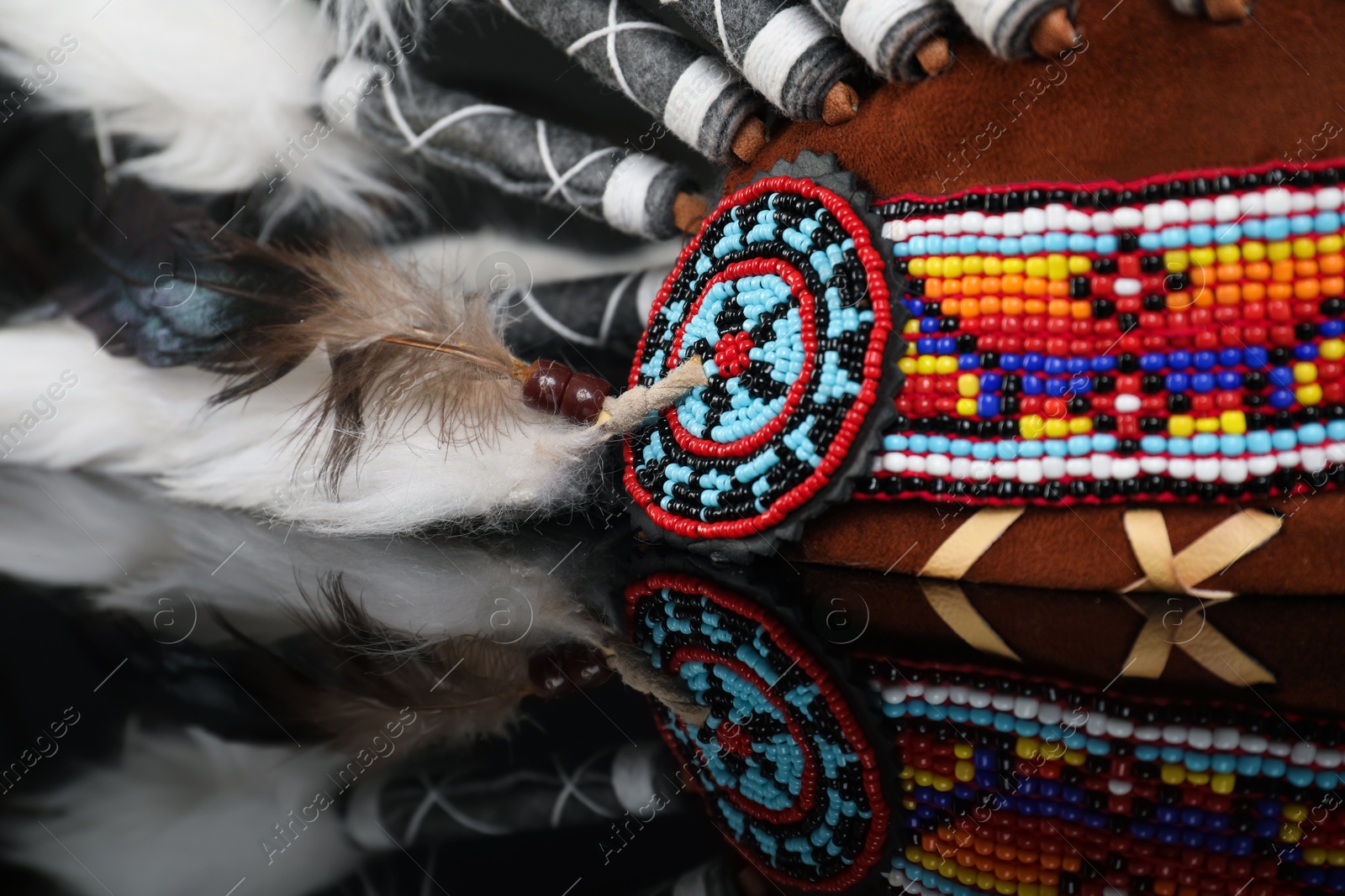 Photo of Traditional warbonnet (Native American chief headdress) on black mirror surface, closeup
