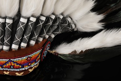Photo of Traditional warbonnet (Native American chief headdress) on black mirror surface, closeup