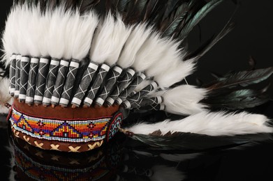 Photo of Traditional warbonnet (Native American chief headdress) on black mirror surface, closeup