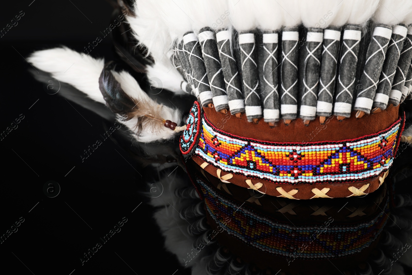 Photo of Traditional warbonnet (Native American chief headdress) on black mirror surface, closeup
