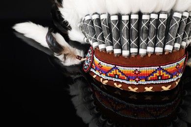 Photo of Traditional warbonnet (Native American chief headdress) on black mirror surface, closeup