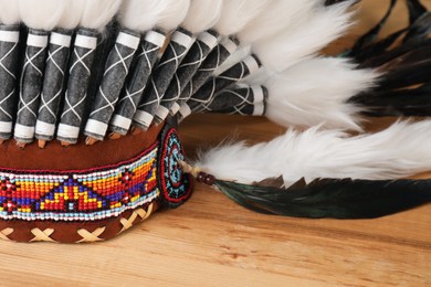 Photo of Traditional warbonnet (Native American chief headdress) on wooden table, closeup