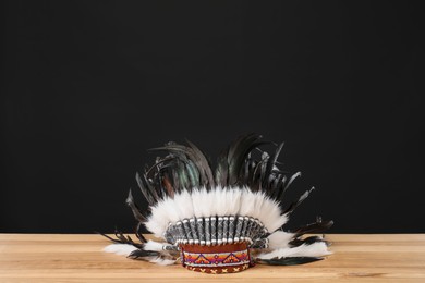 Photo of Traditional warbonnet (Native American chief headdress) on wooden table against black background