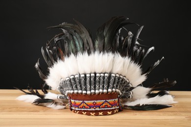 Photo of Traditional warbonnet (Native American chief headdress) on wooden table against black background
