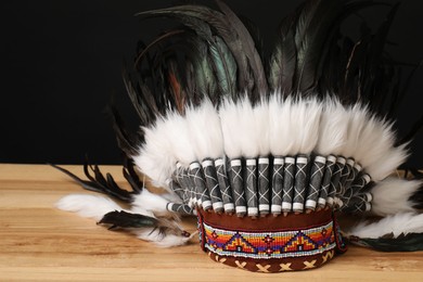 Photo of Traditional warbonnet (Native American chief headdress) on wooden table against black background