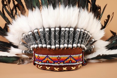 Photo of Traditional warbonnet (Native American chief headdress) on beige background, closeup
