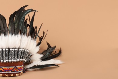Photo of Traditional warbonnet (Native American chief headdress) on beige background, space for text
