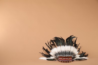 Photo of Traditional warbonnet (Native American chief headdress) on beige background, space for text