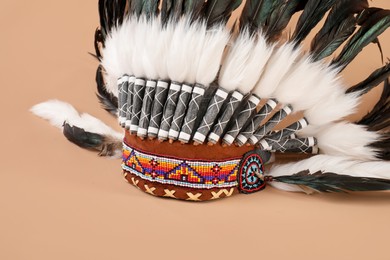 Photo of Traditional warbonnet (Native American chief headdress) on beige background, closeup