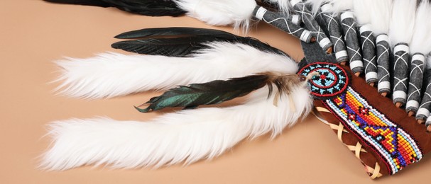 Photo of Traditional warbonnet (Native American chief headdress) on beige background, closeup