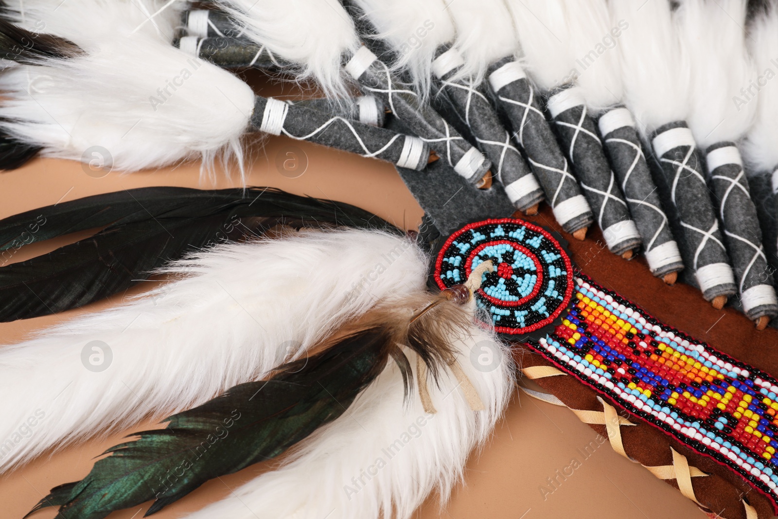 Photo of Traditional warbonnet (Native American chief headdress) on beige background, closeup