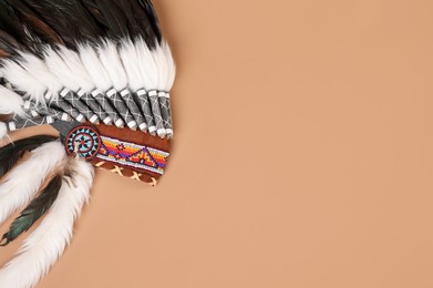 Photo of Traditional warbonnet (Native American chief headdress) on beige background, top view. Space for text