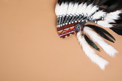 Photo of Traditional warbonnet (Native American chief headdress) on beige background, top view. Space for text