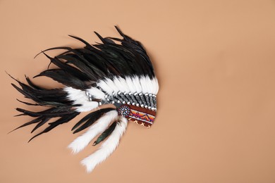 Photo of Traditional warbonnet (Native American chief headdress) on beige background, top view. Space for text