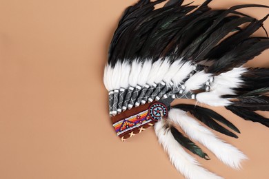Photo of Traditional warbonnet (Native American chief headdress) on beige background, top view. Space for text