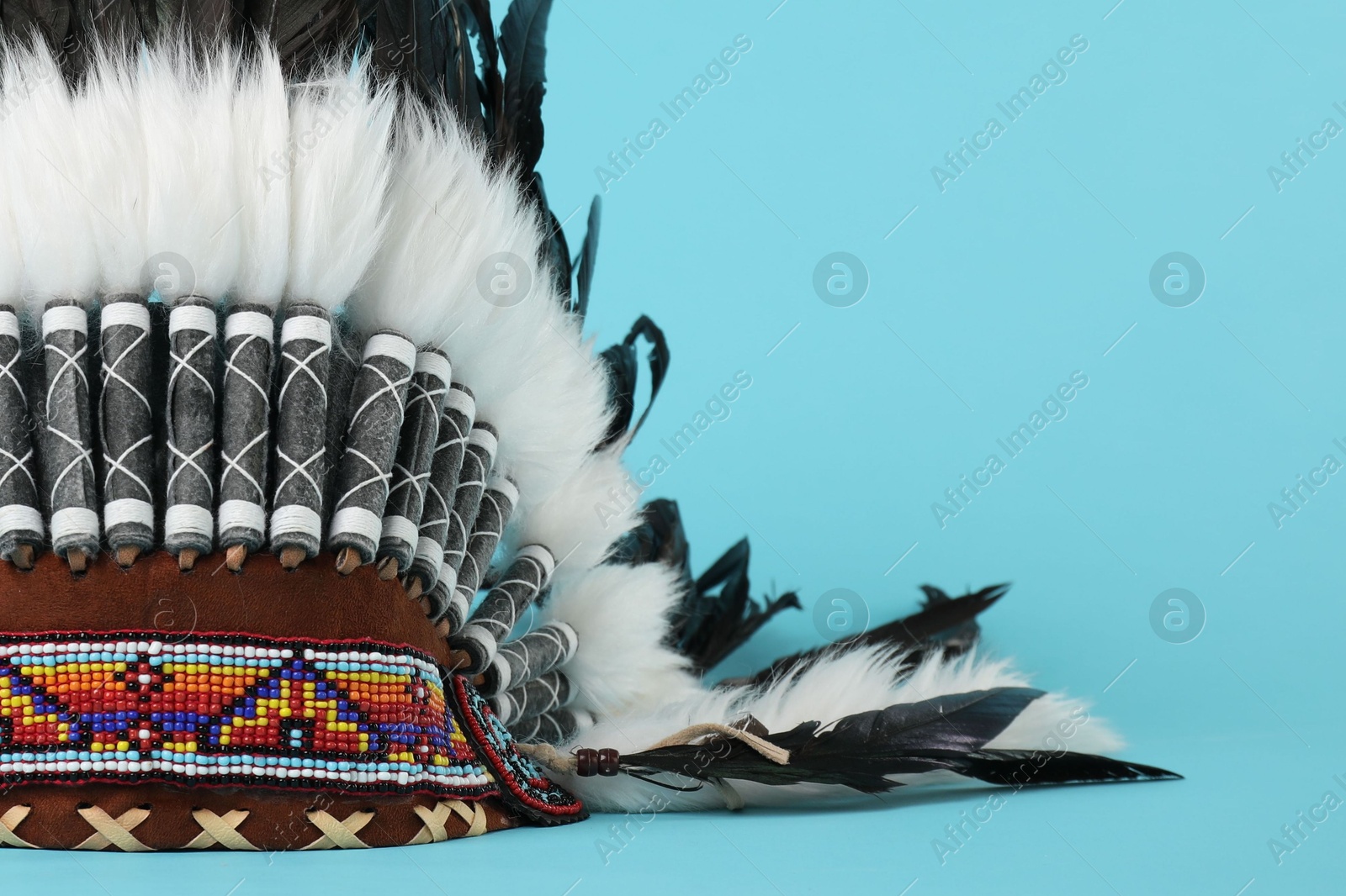 Photo of Traditional warbonnet (Native American chief headdress) on light blue background, closeup. Space for text