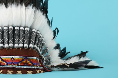 Photo of Traditional warbonnet (Native American chief headdress) on light blue background, closeup. Space for text