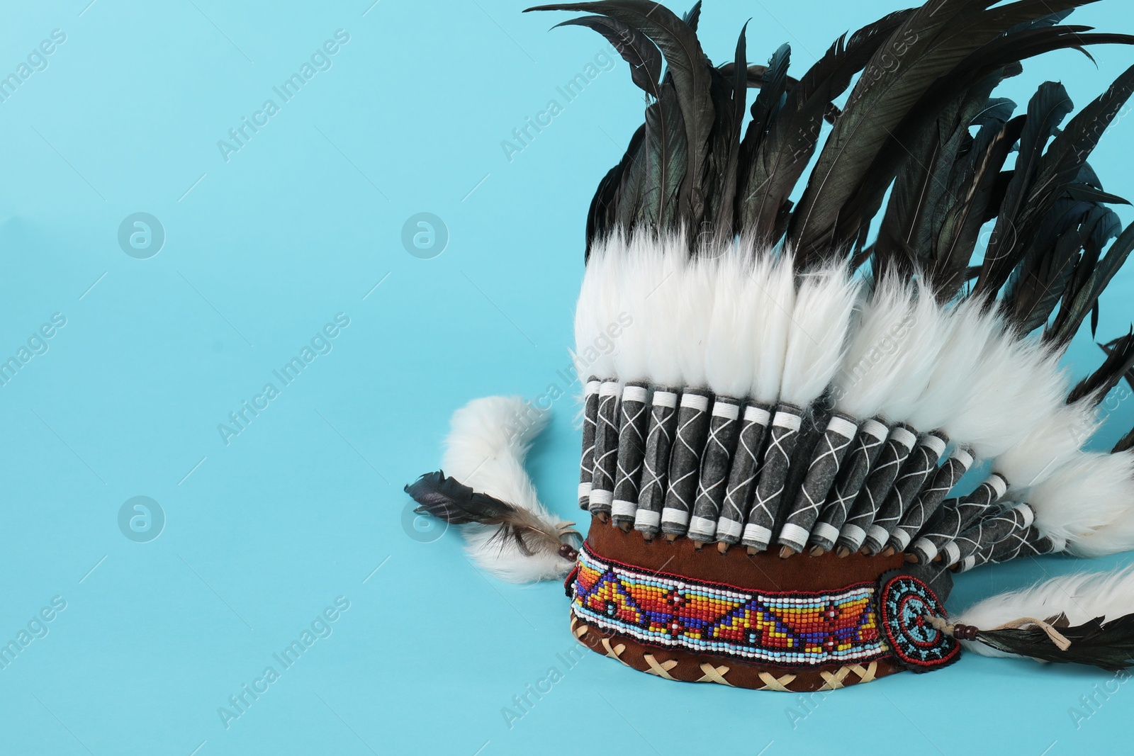 Photo of Traditional warbonnet (Native American chief headdress) on light blue background, space for text