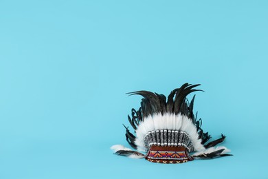 Photo of Traditional warbonnet (Native American chief headdress) on light blue background, space for text