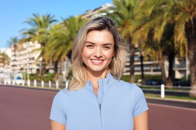 Photo of Portrait of happy young woman in sportswear outdoors