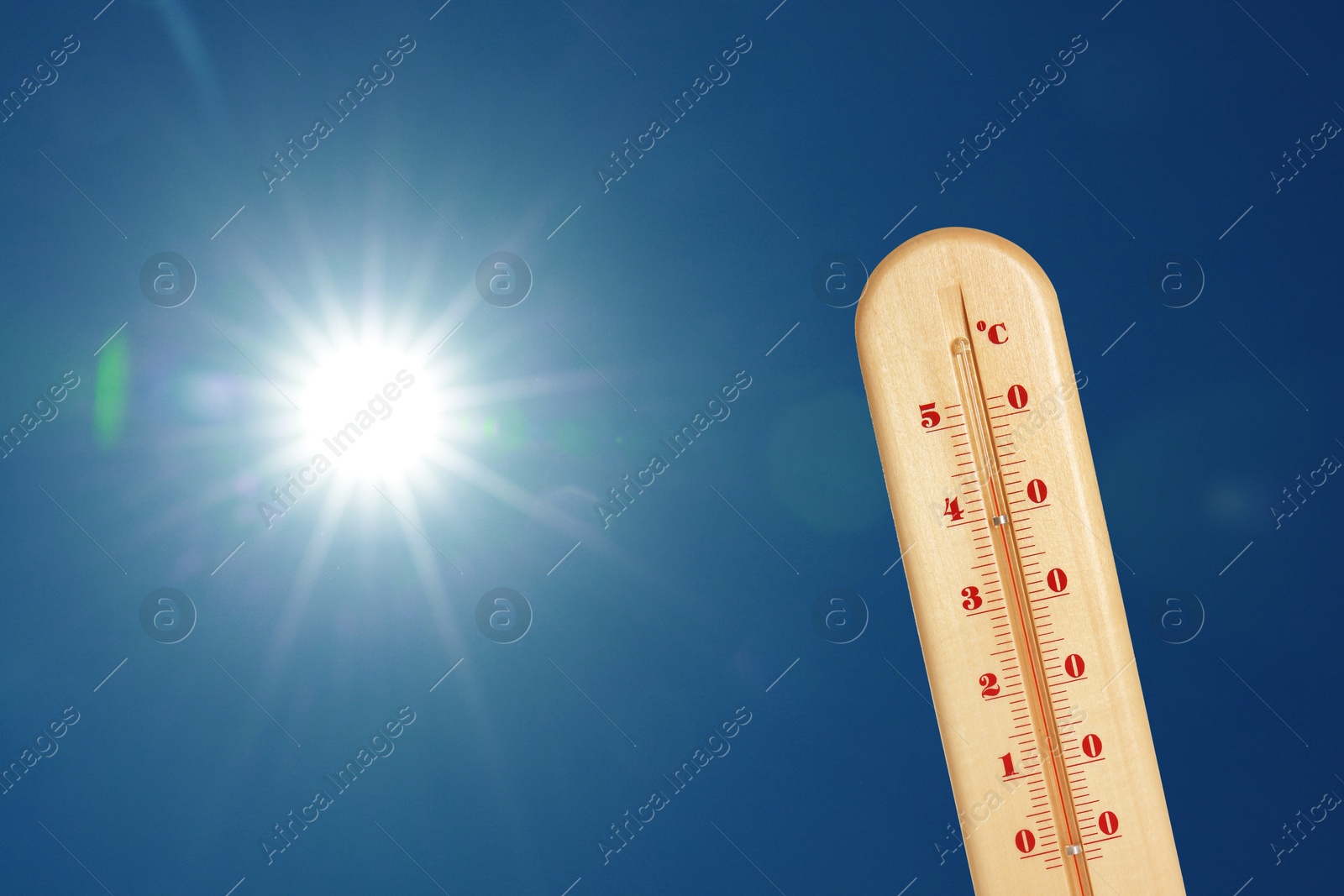 Image of Thermometer showing high temperature against sky with bright sun. Extremely hot weather