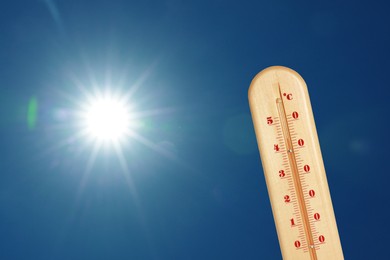 Image of Thermometer showing high temperature against sky with bright sun. Extremely hot weather