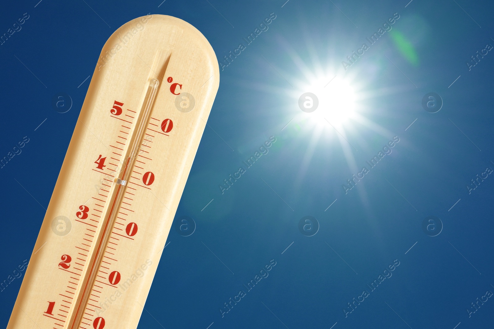 Image of Thermometer showing high temperature against sky with bright sun. Extremely hot weather