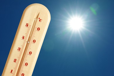 Image of Thermometer showing high temperature against sky with bright sun. Extremely hot weather