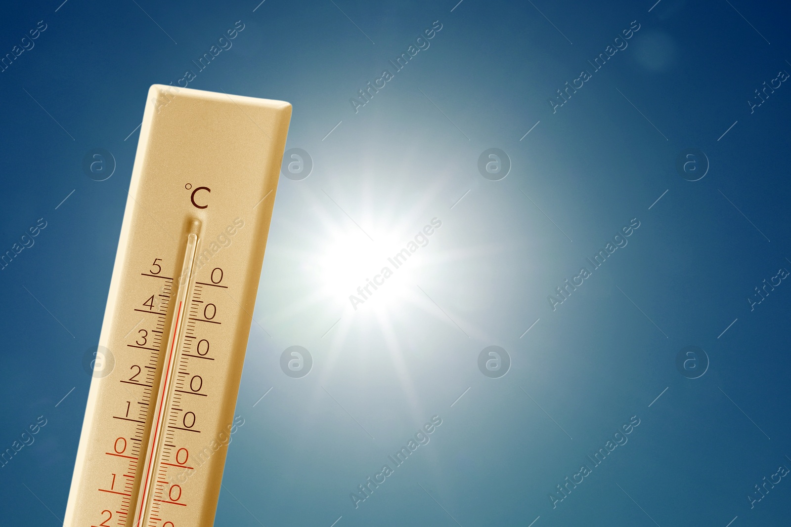 Image of Thermometer showing high temperature against sky with bright sun. Extremely hot weather