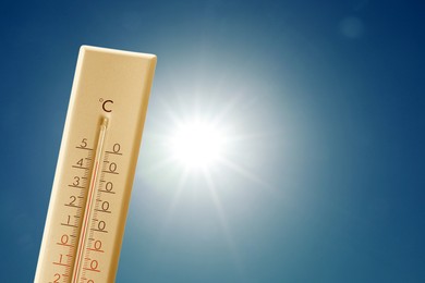Image of Thermometer showing high temperature against sky with bright sun. Extremely hot weather