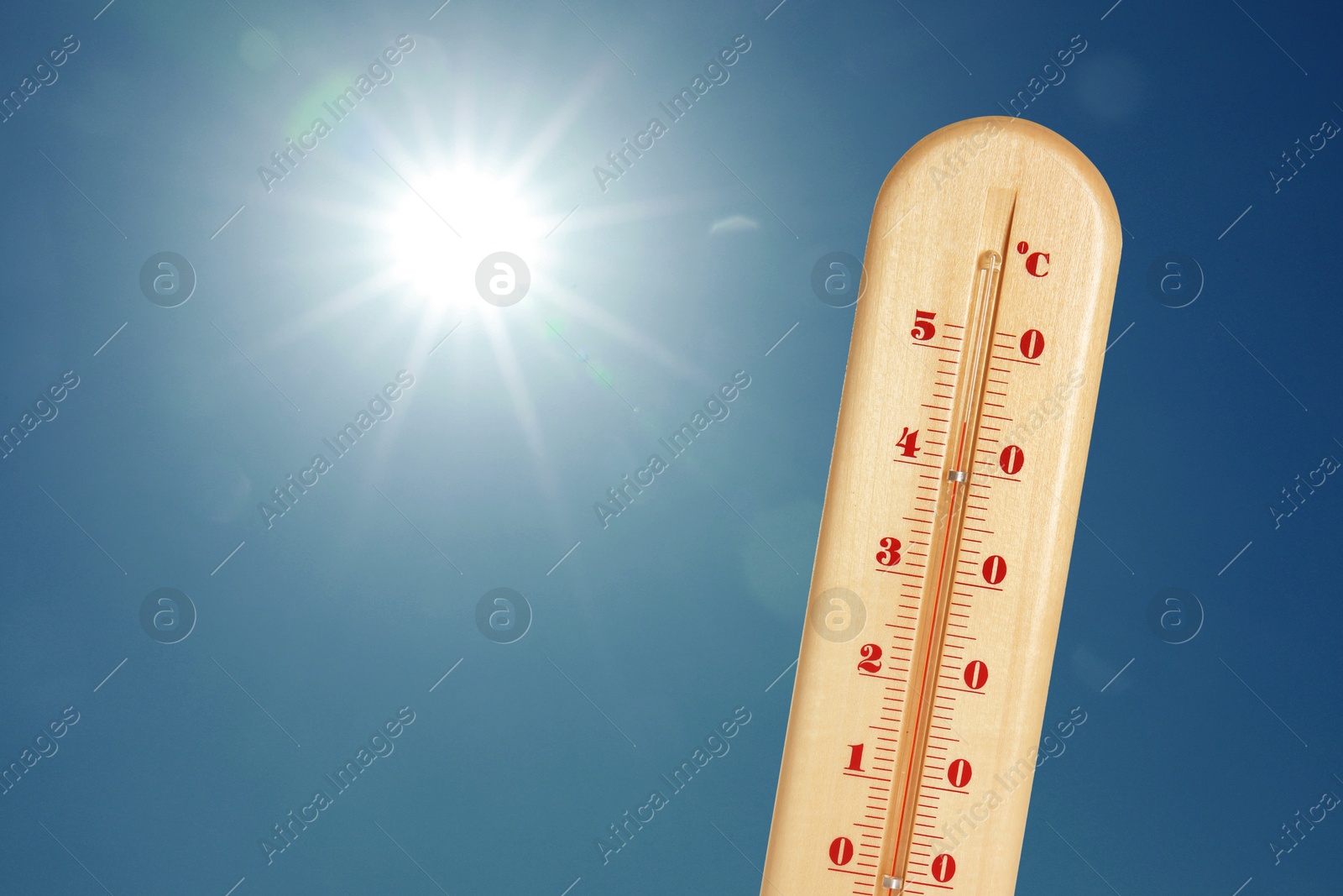 Image of Thermometer showing high temperature against sky with bright sun. Extremely hot weather