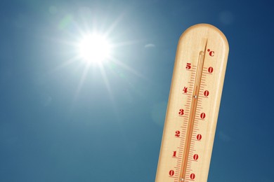 Image of Thermometer showing high temperature against sky with bright sun. Extremely hot weather