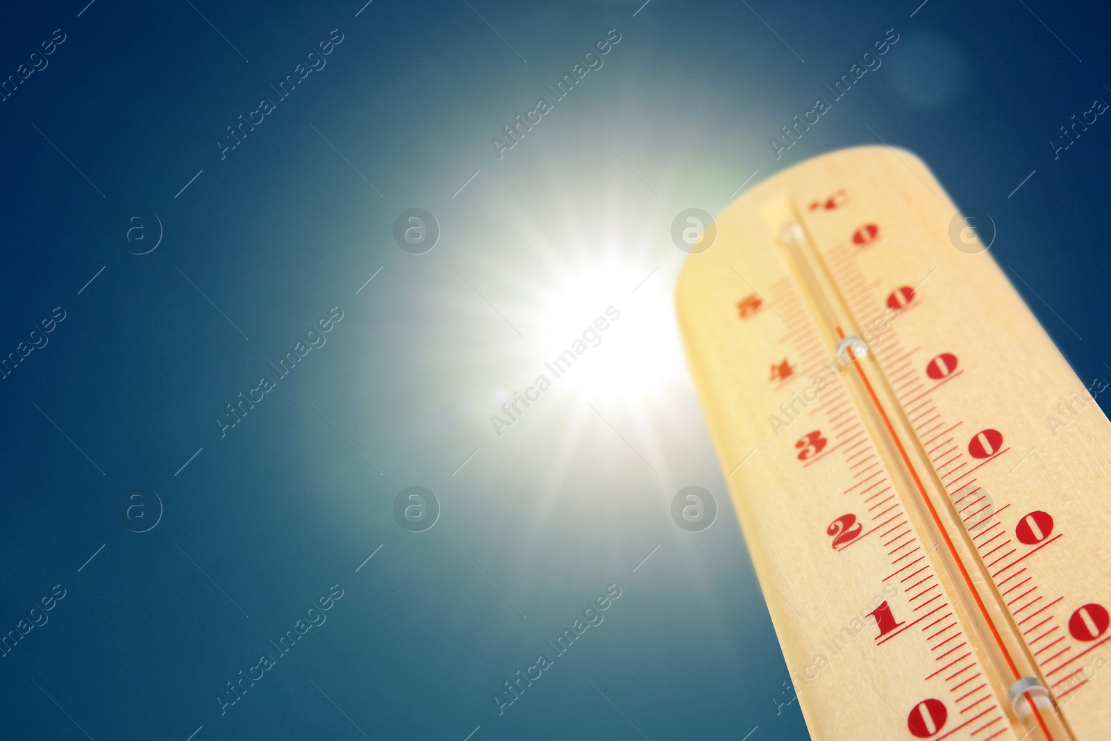 Image of Thermometer showing high temperature against sky with bright sun. Extremely hot weather